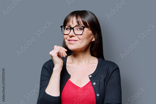Headshot portrait of smiling mature woman on grey background