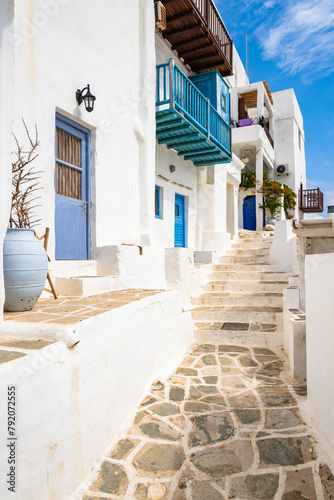 White houses in narrow alley of traditional Kastro village with palm tree in background, Sifnos island, Greece