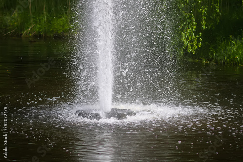 Fountain with flowing water in a summer park.