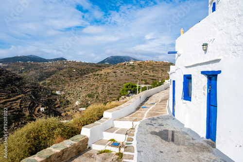 View of Kastro village buildings from coastal promenade with mountain ladscape in background, Sifnos island, Greece