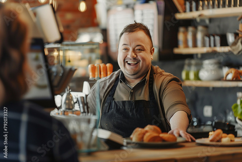 A man with a big smile is standing behind a counter in a coffee shop. He is wearing an apron and he is happy