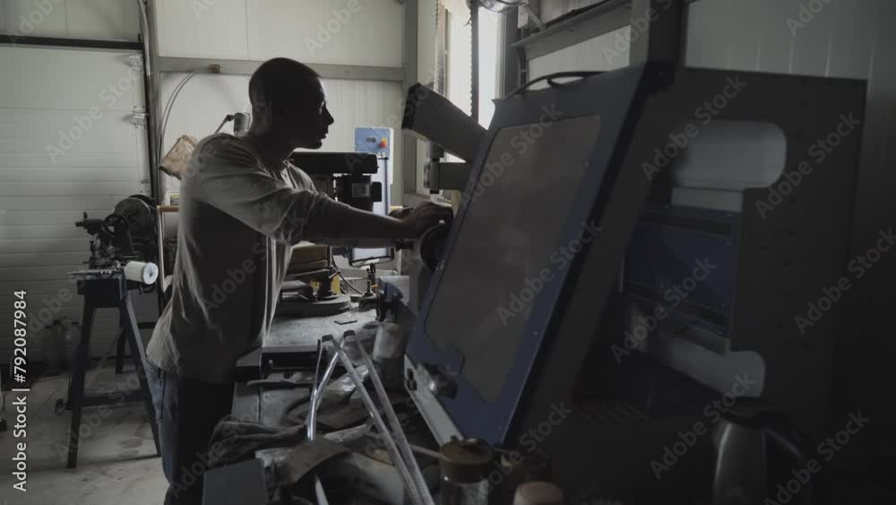 Worker Setting up the modern saw sharpening equipment. A Laborer is operating the saw sharpening equipment at the manufacturing facility. Saw sharpening equipment at the production workshop. Factory.