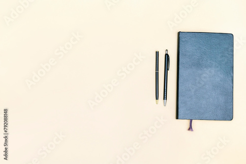 Black blank notebook, pen on beige background.Top view desk arrangement.Time management,planning concept. Minimal style, mock up with copy space, template logo design