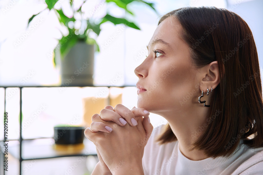 Excited sad upset young woman with folded hands, face in profile close-up Excited sad upset young woman with folded hands, face in profile close-up