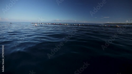 Tracking shot of large group of canoes in open ocean photo