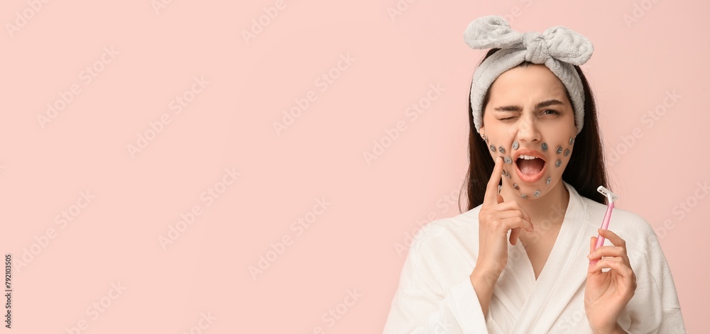 Displeased young woman with thumb tacks on face and razor against pink background with space for text. Depilation concept Displeased young woman with thumb tacks on face and razor against pink background with space for text. Depilation concept