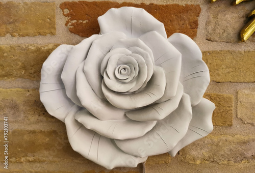 Rosa bianca ornamentale appesa a un muro di mattoni in gesso e marmo   photo