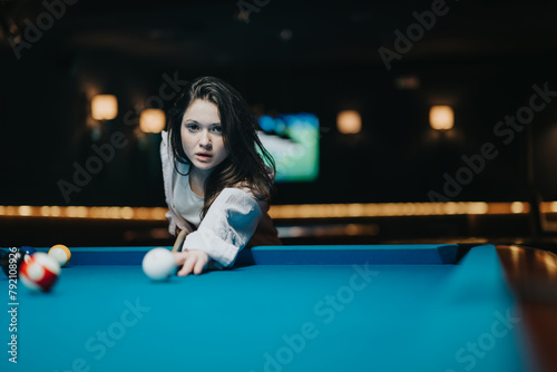 Intense concentration captured as a young woman lines up her shot at a pool table in a moody bar atmosphere. photo