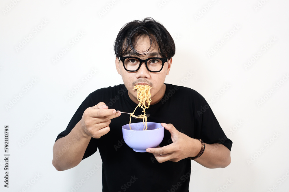 Adult Asian man showing happy expression while eating a bowl of noodle Adult Asian man showing happy expression while eating a bowl of noodle