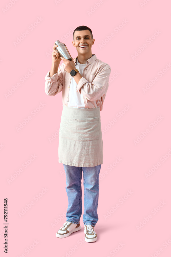 Young male bartender with shaker on pink background Young male bartender with shaker on pink background