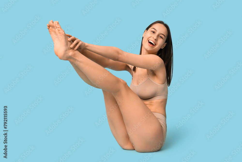 Obraz premium Beautiful young woman in underwear sitting on blue background