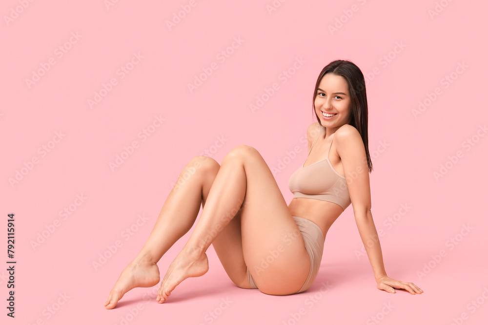 Beautiful young woman in beige underwear on pink background