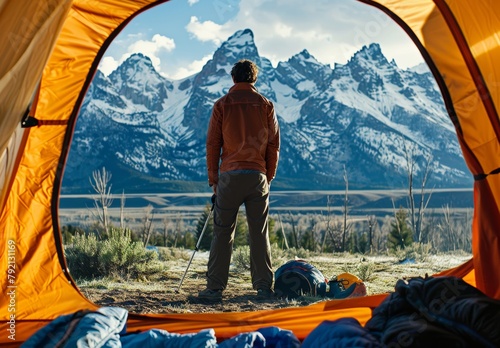 Man Standing in Front of Tent With Mountains in Background