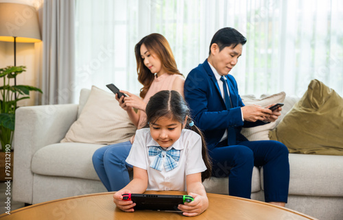 Family don't care about each other. Asian parents ignore their child and looking at their mobile phone at home, gadgets dependence overuse internet social media addiction on sofa living room