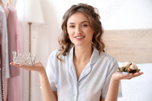 Beautiful young happy woman with crown and boutonniere for prom night in bedroom