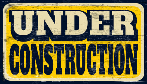 Aged and worn under construction sign on wood
