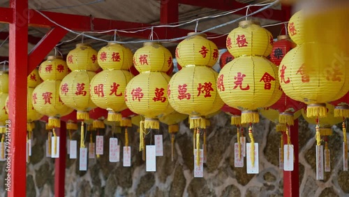 Closeup of a row of Chinese yellow lanterns that say Happy New Year, hanging in a row with parallax tracking movement