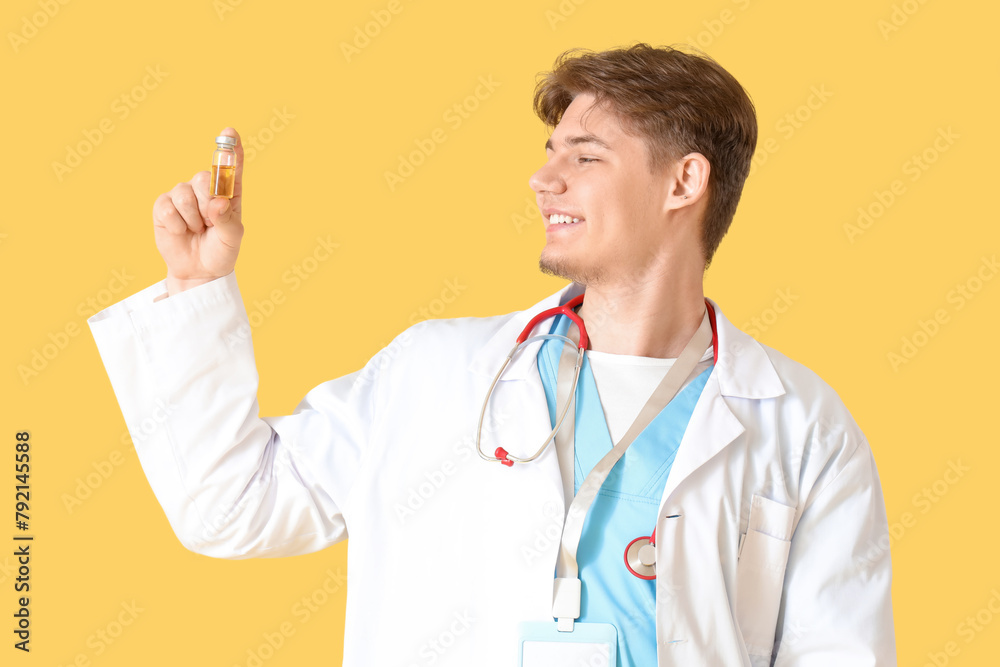 Male medical intern with ampule on yellow background Male medical intern with ampule on yellow background
