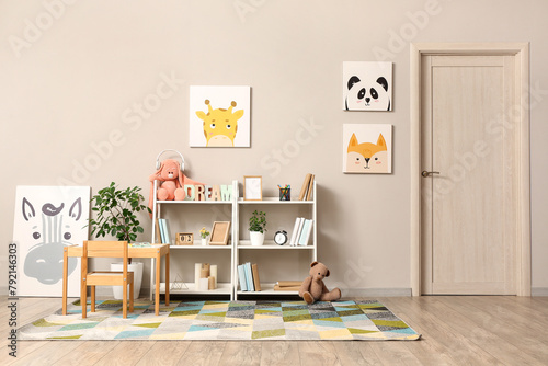 Interior of children room with toys, pictures, table and shelving units