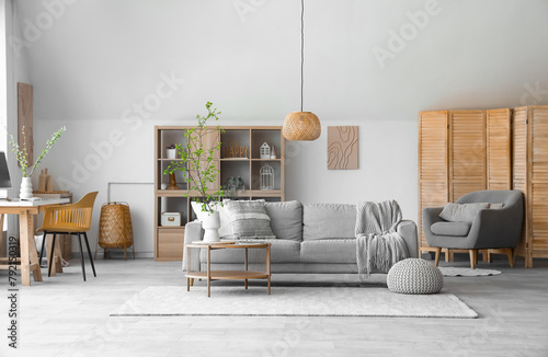 Interior of stylish living room with cozy sofa, coffee table and blooming tree branches in vase
