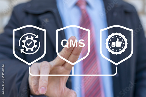 Business man working on virtual touch screen presses abbreviation: QMS. Quality Management System ( QMS ) concept. Formalized system for achieving quality policies and objectives. photo