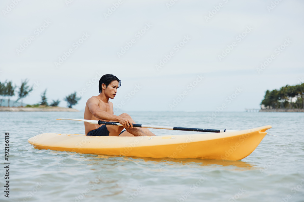 Asian Man Kayaking in Tropical Paradise: Adventures on the Beach