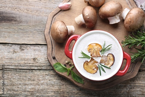 Delicious homemade mushroom soup in ceramic pot and fresh ingredients on wooden table, flat lay. Space for text