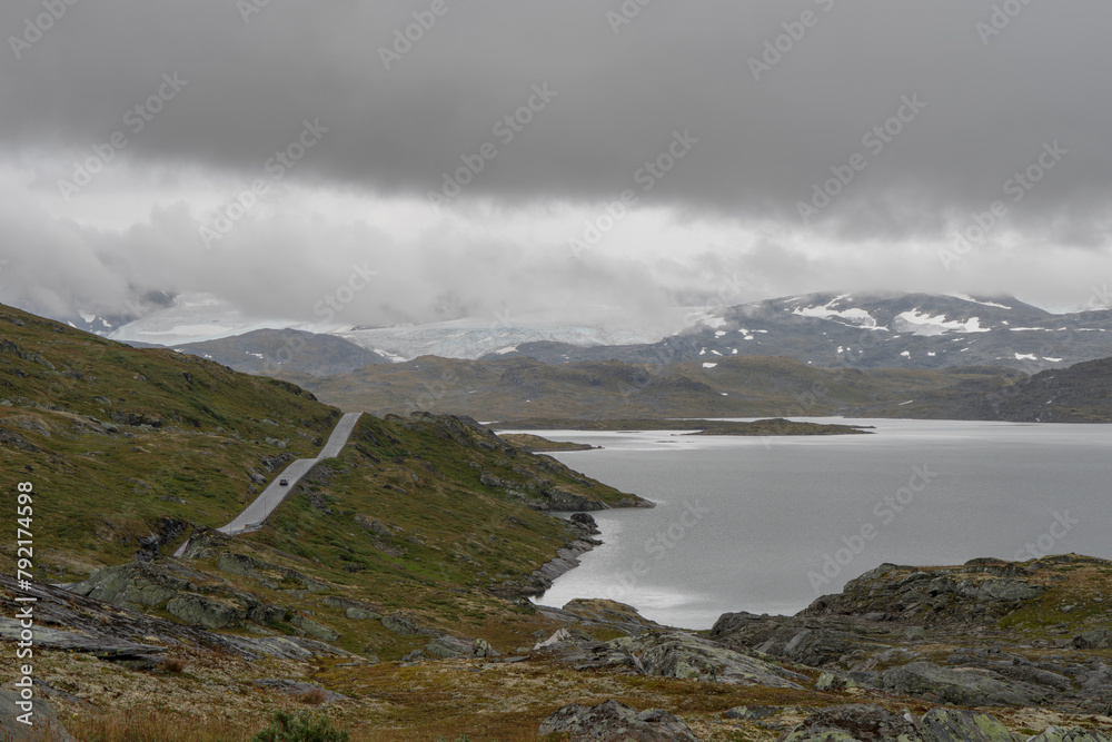 Roadtrip in Norway with solitary car and lake and glacier in the background