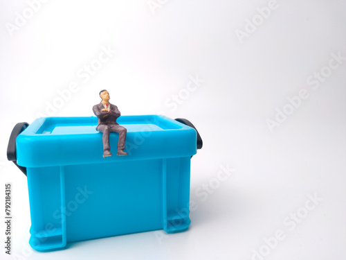 Miniature people are sitting on a blue miniature storage basket box