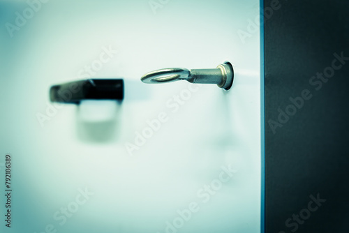 Focused closely on a key inserted into a lock, the blurred background featuring a door handle enhances the concept of security