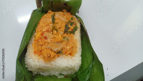 a packet of grilled rice wrapped in banana leaves, grilled over a charcoal fire filled with rice flavored with turmeric and other spices, anchovies and basil leaves, served warm.

