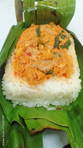a packet of grilled rice wrapped in banana leaves, grilled over a charcoal fire filled with rice flavored with turmeric and other spices, anchovies and basil leaves, served warm.

