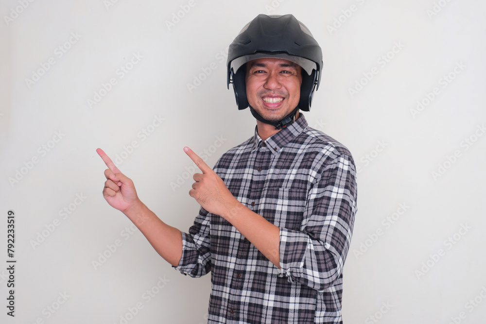 Fototapeta premium A man wearing motorcycle helmet smiling and pointing beside him