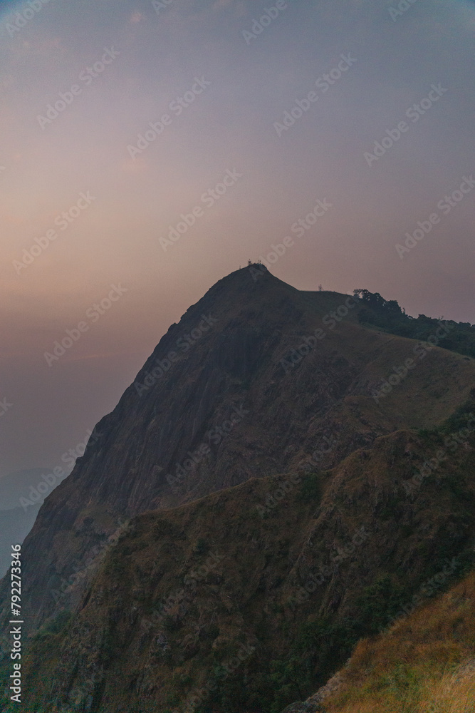 A mountain with a cloudy sky in the background A mountain with a cloudy sky in the background