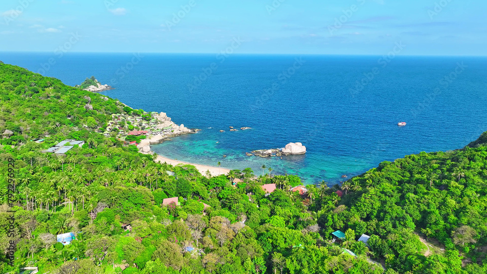 A coastal sanctuary where verdant foliage meets rugged rocks, kissed by azure waves. Serenity reigns under swaying coconut palms. Flying from drone. Koh Tao, Southern Thailand. Nature background.

