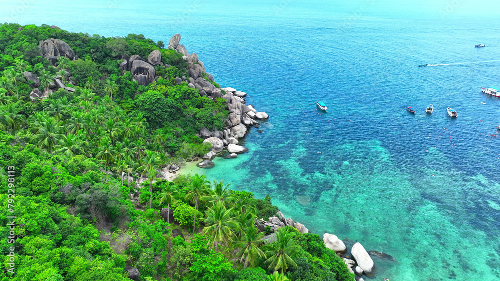 Drone glides over a ship, tourists snorkel in azure waters, enveloped by a lush tropical haven. Nature's masterpiece. Koh Tao, Surat Thani Province, Southern Thailand. Sea background. 
