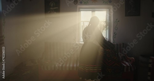 Young Girl in Ethnic Ukrainian Attire by Sunlit Window in Traditional House photo