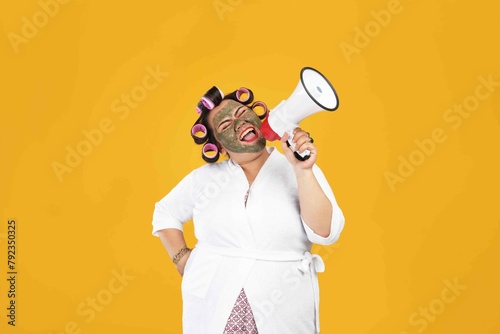 Portrait of a fat housewife wearing a natural mask and holding a megaphone isolated on a yellow color background