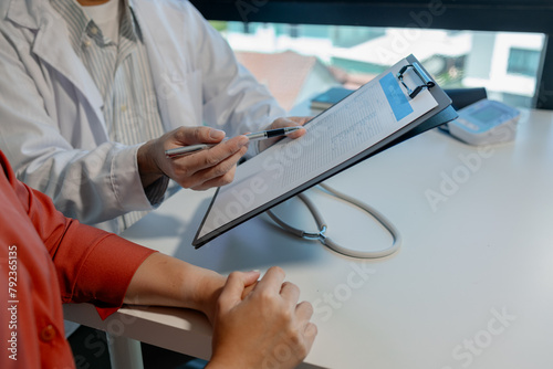 A doctor is explaining blood test results to patient about what diseases were found and what treatment is needed in office, patient is listening to doctor explain the results of the examination.