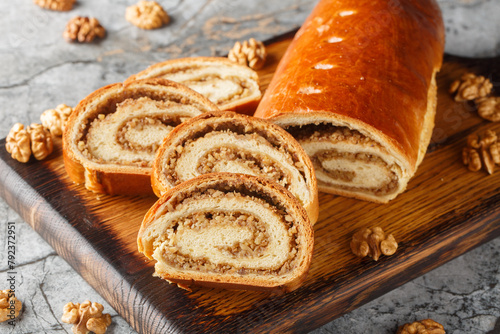 Sliced walnut roll made from yeast dough close-up on a wooden board on the table. Horizontal photo