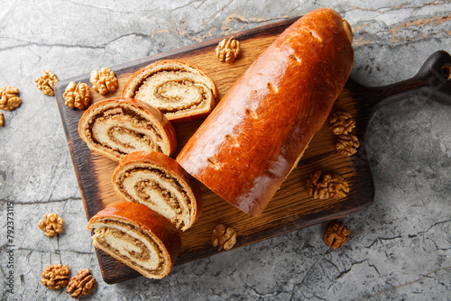 Festive nut roll made from yeast dough with walnuts and honey close-up on a wooden board on the table. Horizontal top view from above