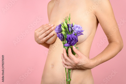 Unrecognizable woman covers her chest with some flowers on an isolated pink background