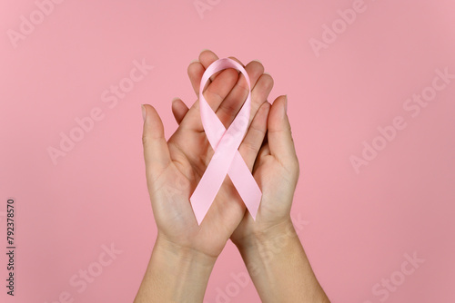 woman's hands with a pink ribbon. concept of fighting breast cancer