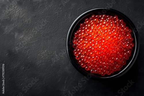 Red caviar in black bowl viewed from above on dark background looks appetizing
