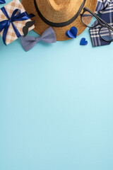 Father's Day celebration vertical setup featuring a straw hat, eyeglasses, gift box, bow tie, and paper hearts on a light blue background