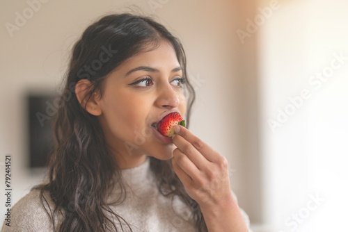 Φωτογραφία indian woman eating strawberry at home