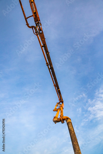 Hose on a deployed crane of a concrete pump track against the sky.