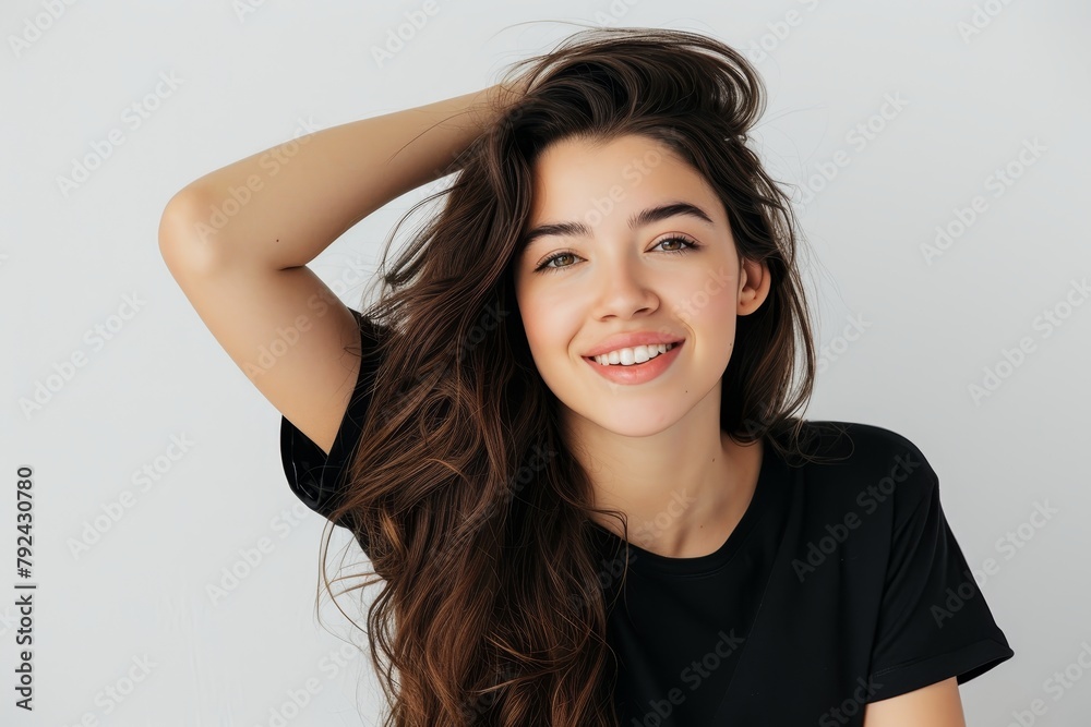 Young woman smiling and looking elegant isolated on a white background in a black t shirt touching her hair Young woman smiling and looking elegant isolated on a white background in a black t shirt touching her hair