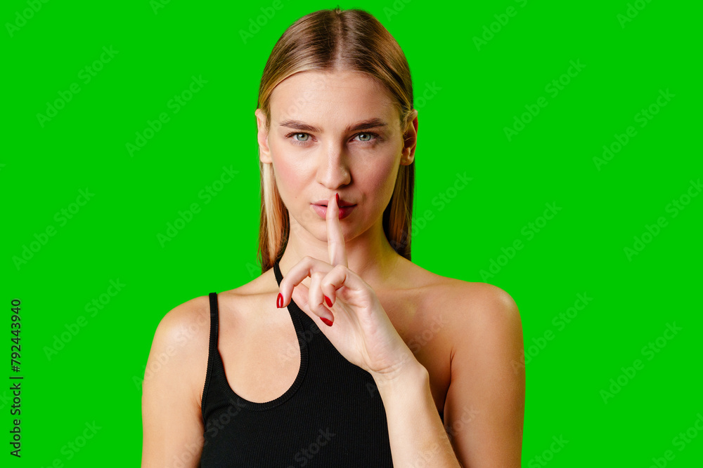 Young Woman Gesturing Silence With Finger on Lips Against Green Screen Background Young Woman Gesturing Silence With Finger on Lips Against Green Screen Background