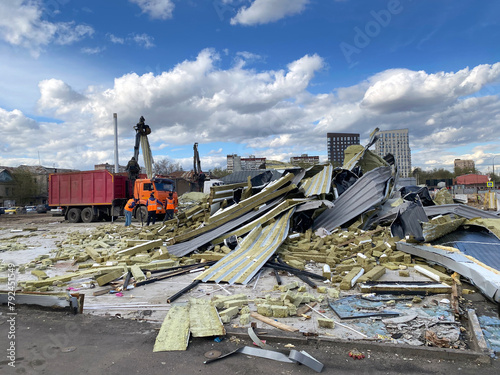 Demolition of illegal commercial buildings. Manipulators load construction debris into trucks. Cell phone photo